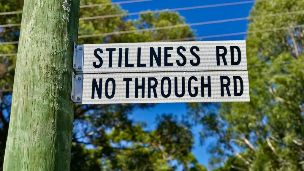 A street sign on a power pole that says 'Stillness Road, No Through Road'