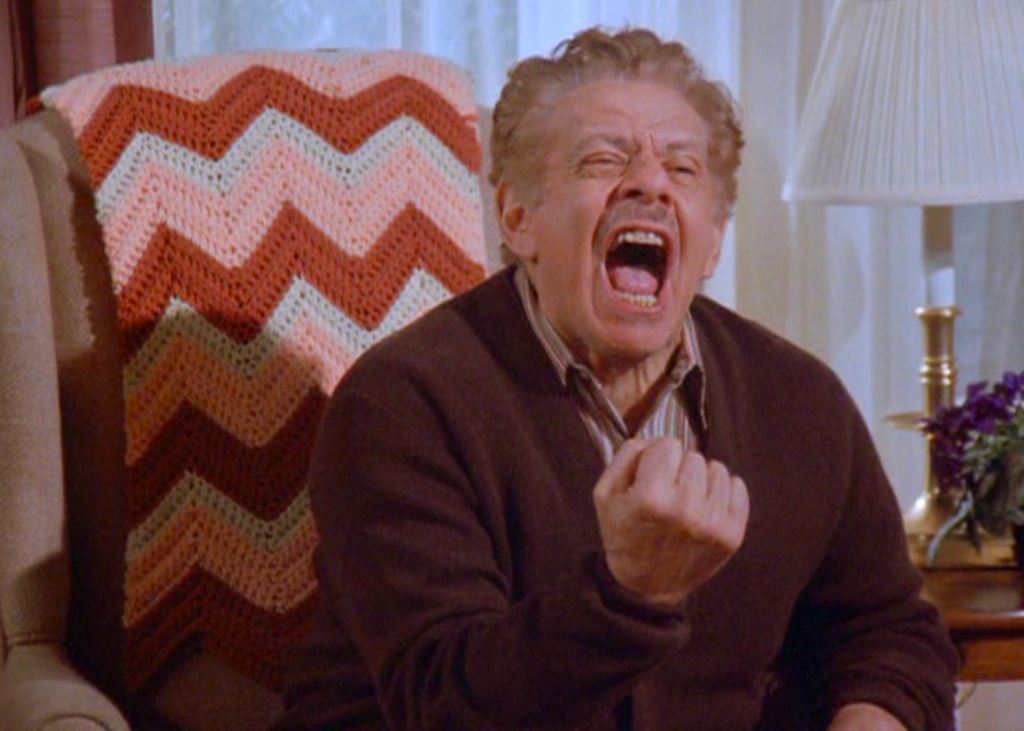 Jerry Stiller as Frank Costanza in Seinfeld, sitting in an armchair during one of his vocal outburts